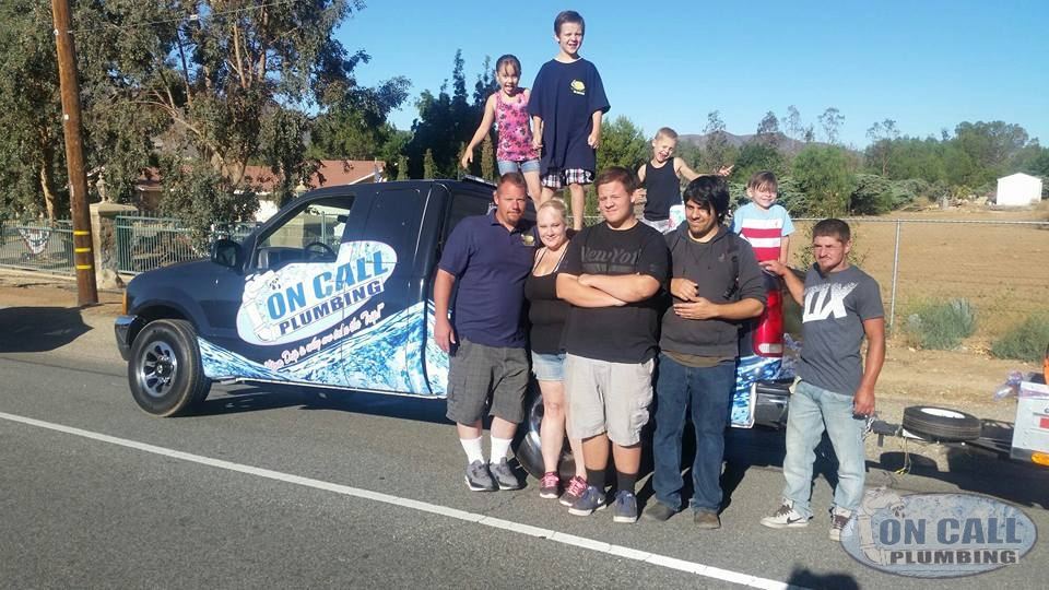 The On Call Plumbing family in front of their wrapped service truck