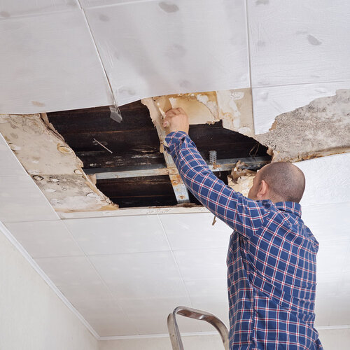 man repairing a water damaged ceiling