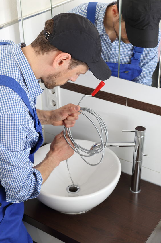 Plumber Cleaning A Pipe Drain With A Spiral Auger